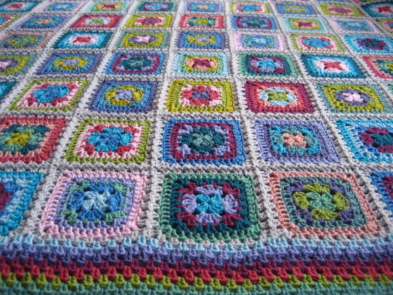 A crocheted blanket made up of multicoloured squares.