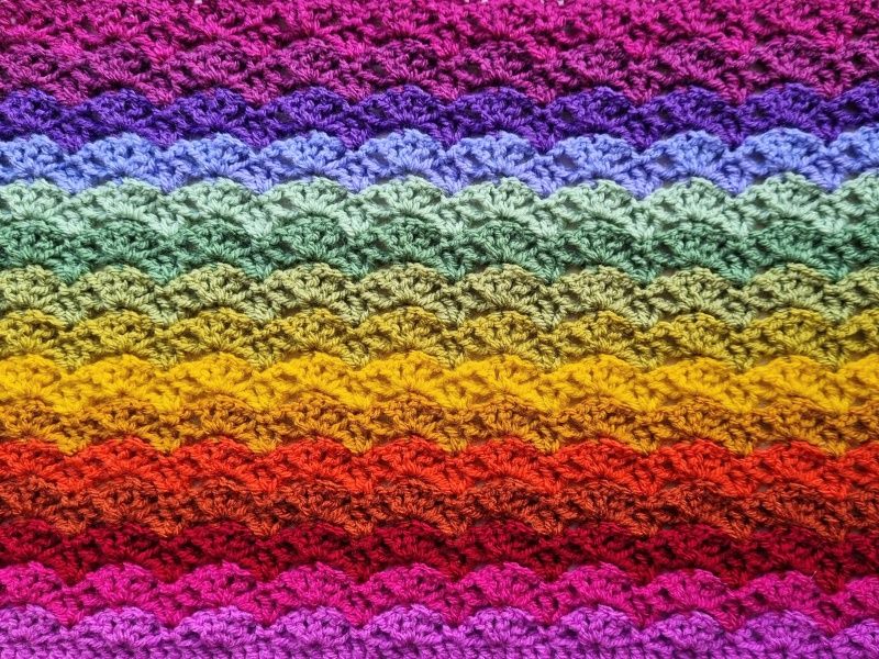 A close up of the crocheted blanket, made up of rainbow coloured rows. 