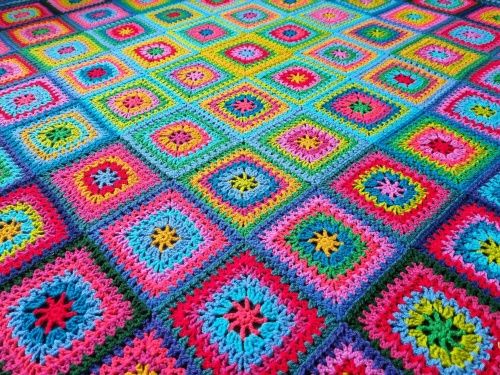 A close up of the crocheted blanket, made up of rainbow coloured squares.
