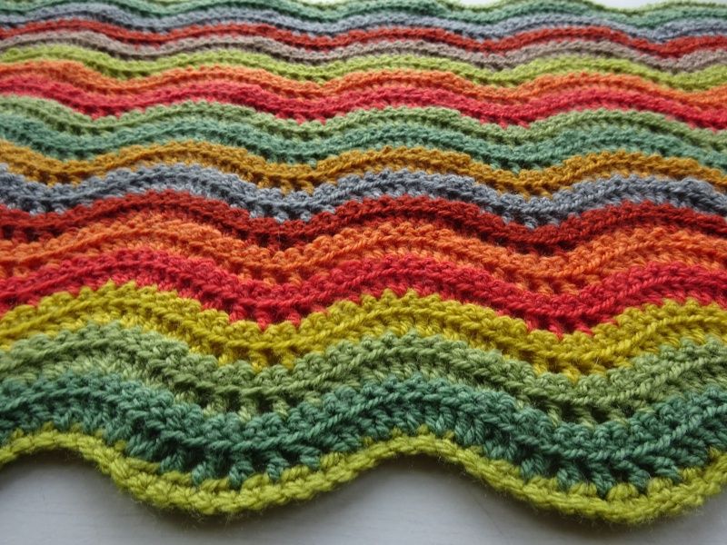 A close up of a striped crochet blanket in shades of green and red.