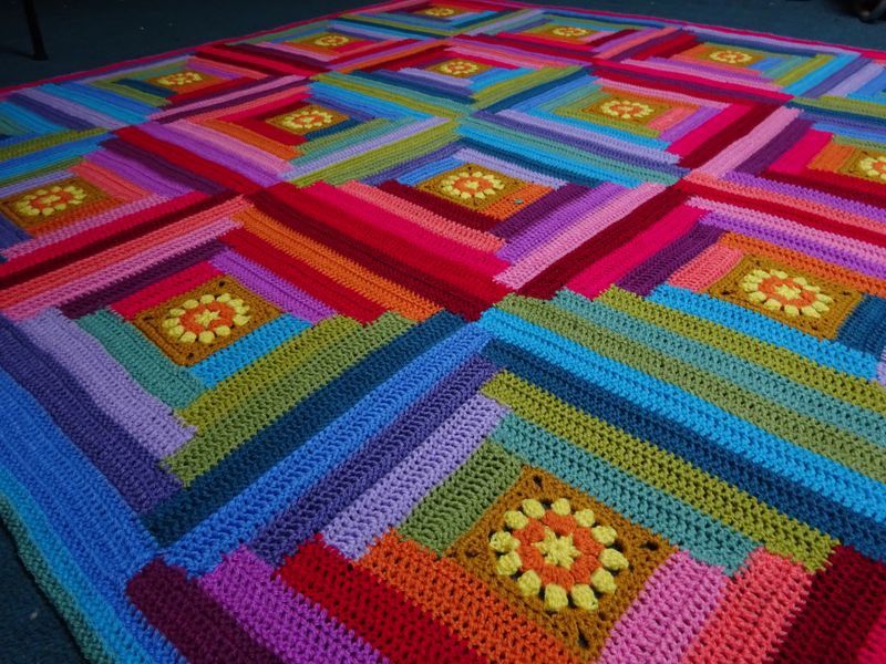 A close up of a crocheted blanket made up of multicoloured squares in rainbow colours.