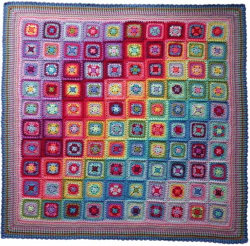 A crocheted blanket made up of squares in various bright colours.