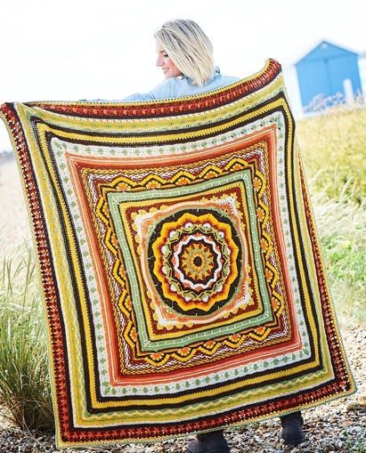 An orange, yellow, brown and green crocheted blanket.