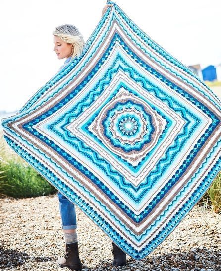 A crocheted blanket in blues, cream and brown.