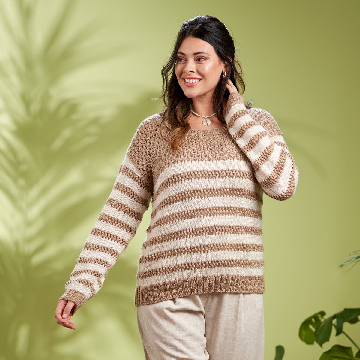 A woman is wearing a light brown and cream striped knitted sweater with lace detail on the brown sections.