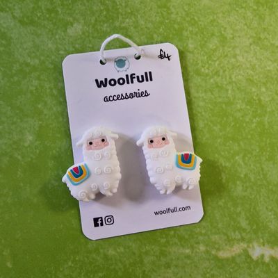 A green background with a pair of alpaca shaped point protectors mounted on a white card.