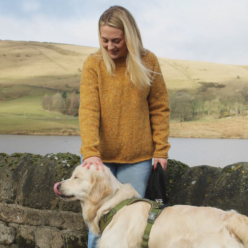 A woman is wearing a mustard yellow knitted sweater.
