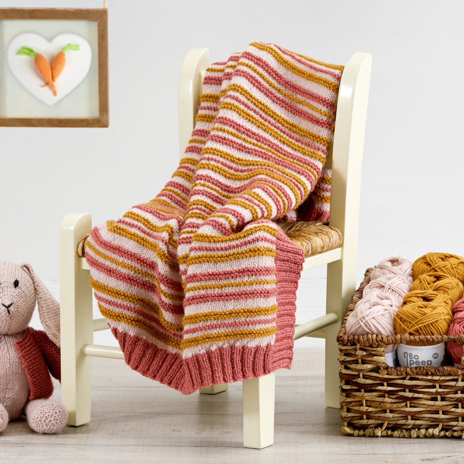 A light pink, red-pink and yellow striped knitted blanket.