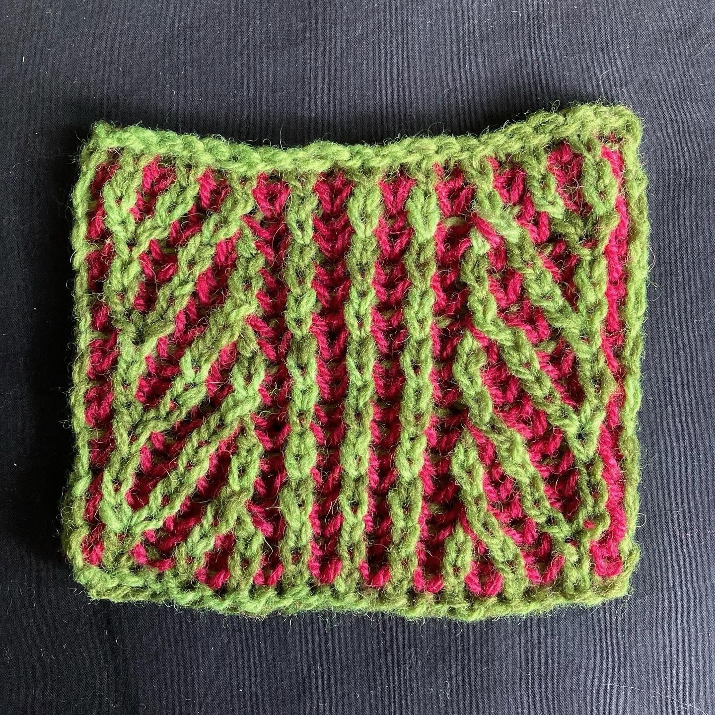 A small green and pink swatch of knitted brioche stitch.