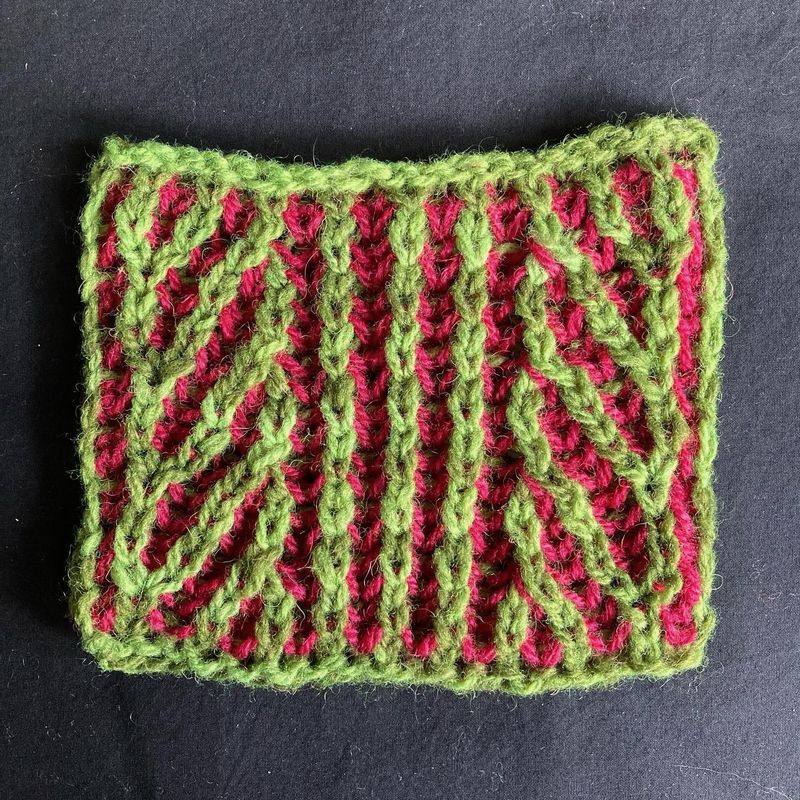 A small green and pink swatch of knitted brioche stitch.