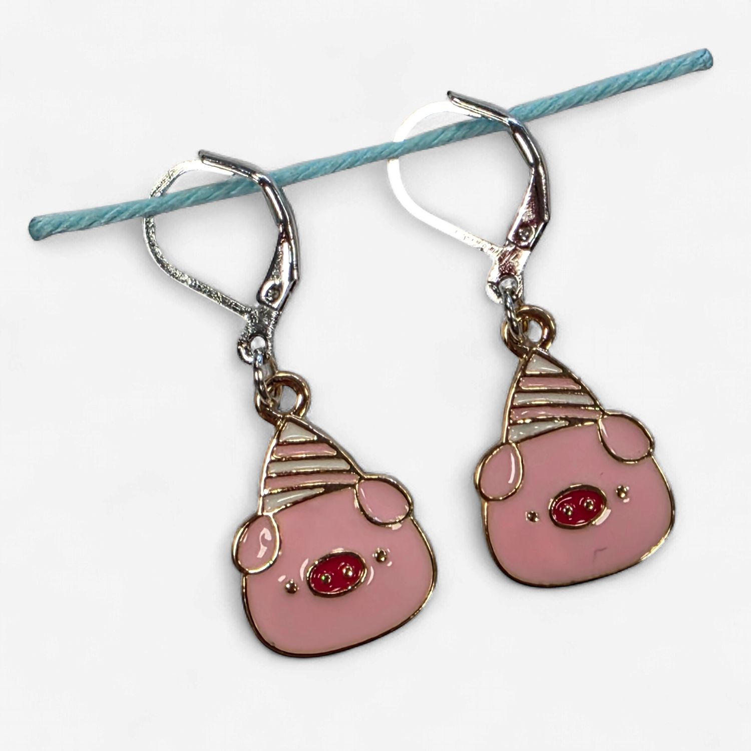 2 pink pig shaped stitch markers with party hats on.