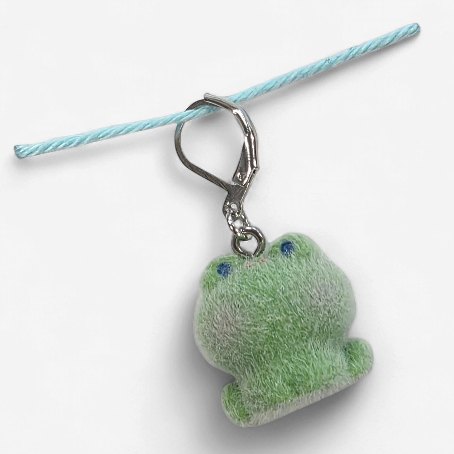 A green fuzzy frog shaped stitch marker.