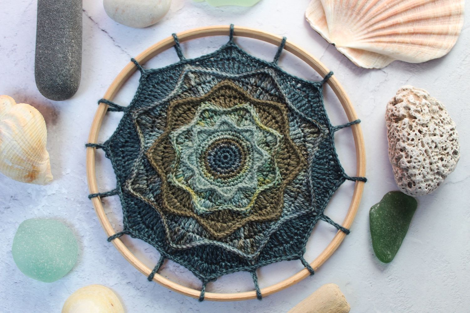 A crocheted mandala in deep teals, blues and greens.