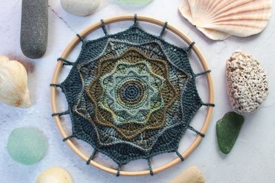 A crocheted mandala in deep teals, blues and greens.