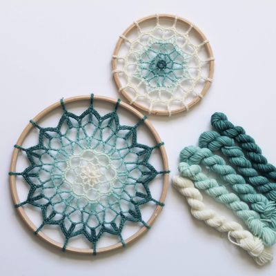 2 crocheted mandalas in cream and blues.