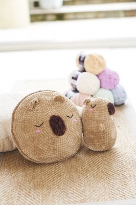 A crocheted capybara face cushion and capybara toy.