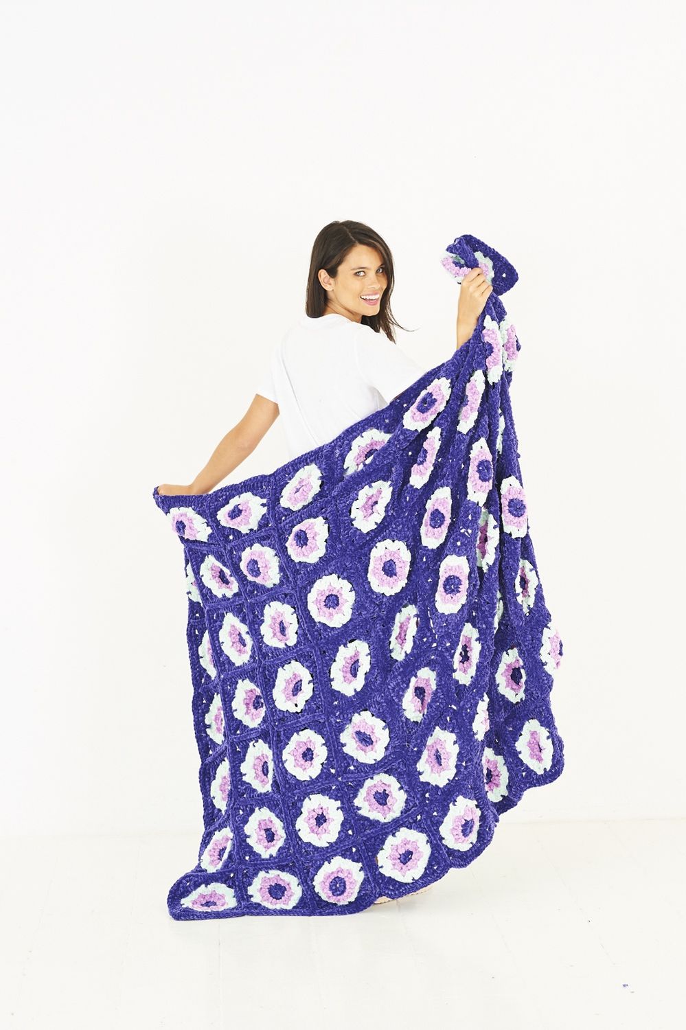 A blue crocheted blanket with white flower motifs.