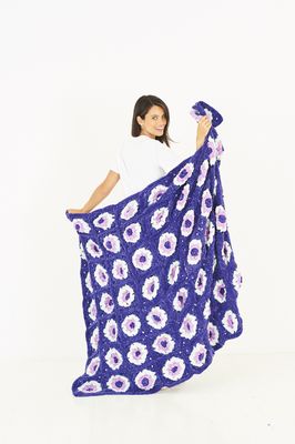 A blue crocheted blanket with white flower motifs.