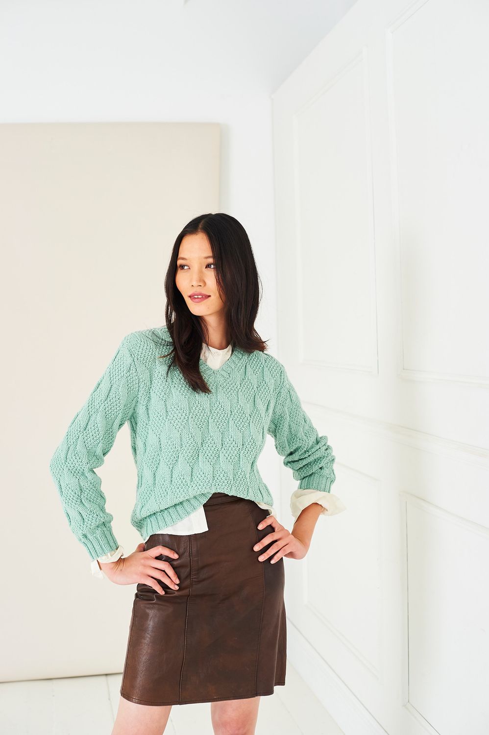 A woman is wearing a mint green knitted sweater.