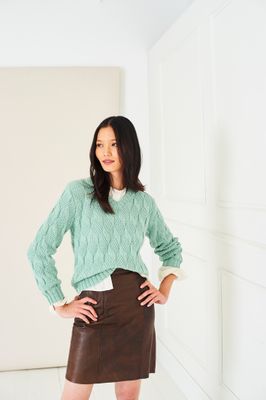A woman is wearing a mint green knitted sweater.