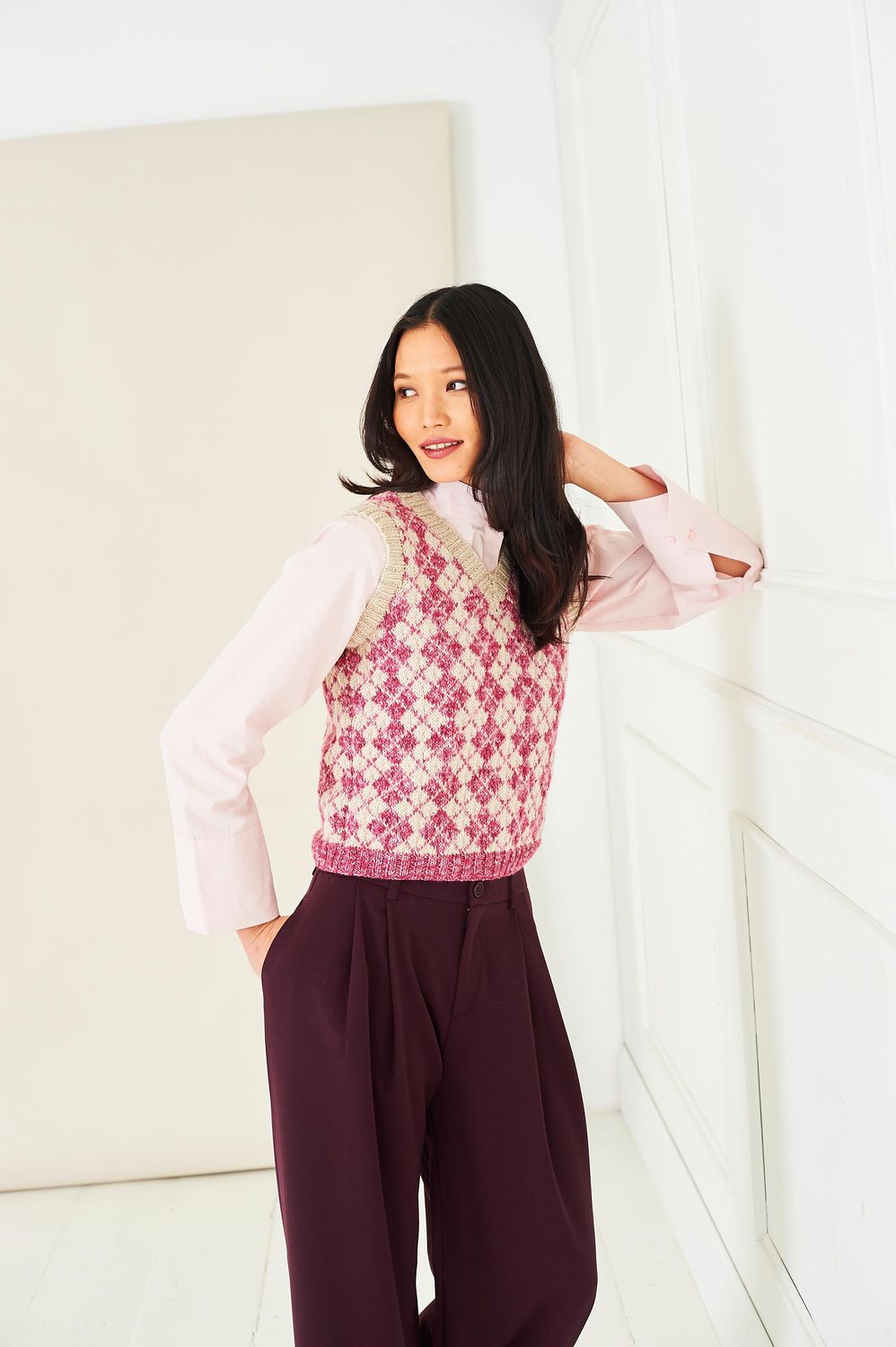 A woman is wearing a beige and pink fair isle knitted tank top.