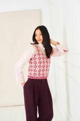 A woman is wearing a beige and pink fair isle knitted tank top.
