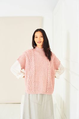 A woman is wearing a pink cable knit tank top.