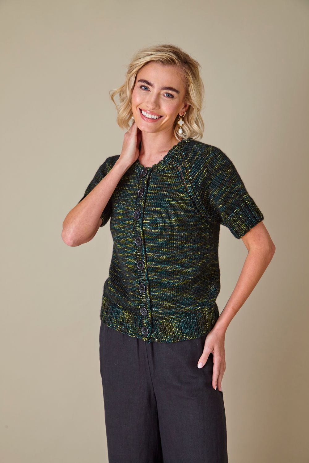 A woman is wearing a dark green knitted cardigan.