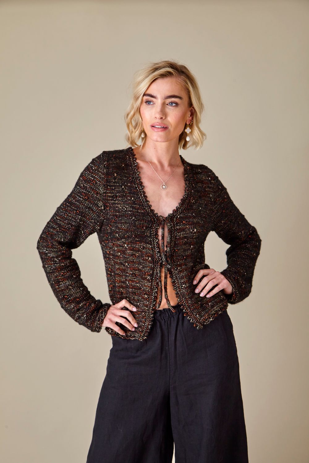 A woman is wearing a dark brown knitted cardigan.