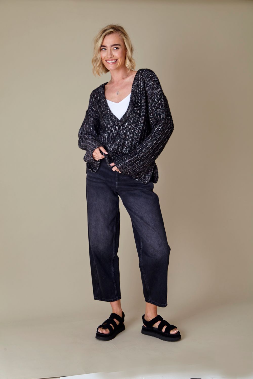 A woman is wearing a dark grey knitted sweater.