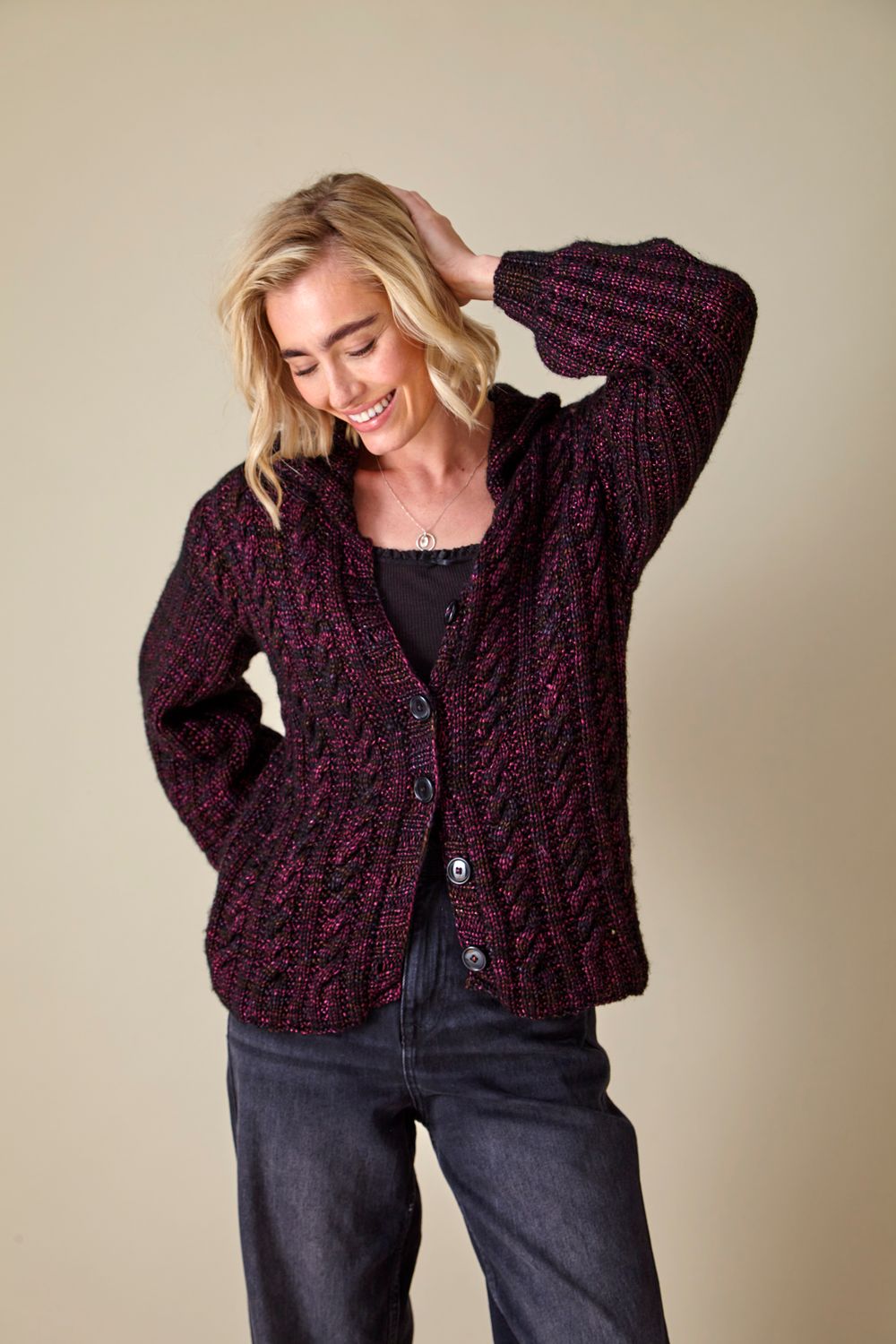 A woman is wearing a dark red knitted cardigan.