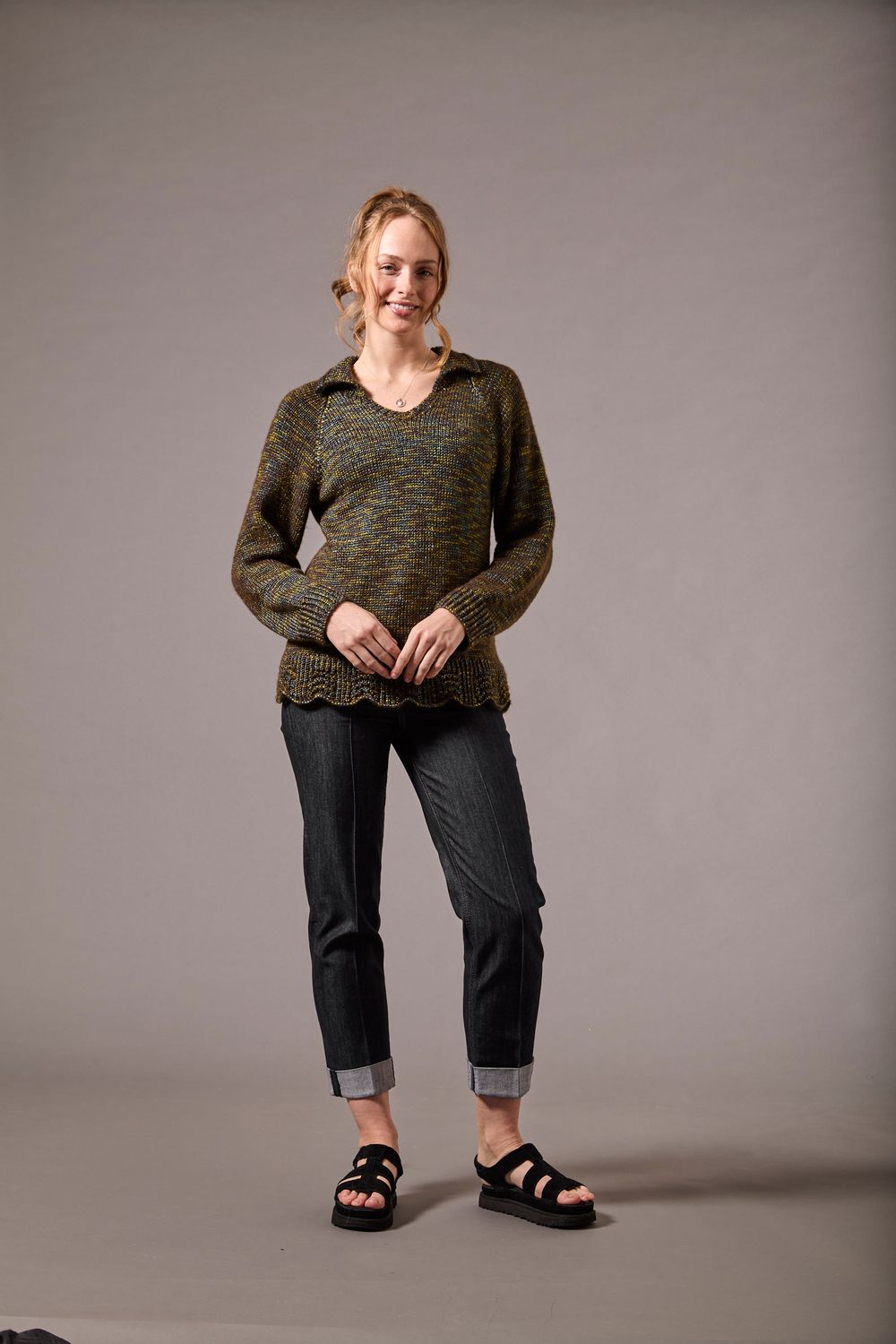 A woman is wearing a dark green knitted sweater.