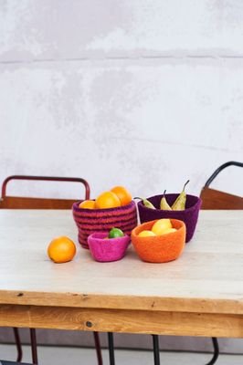 4 felted knitted bowls containing fruit.
