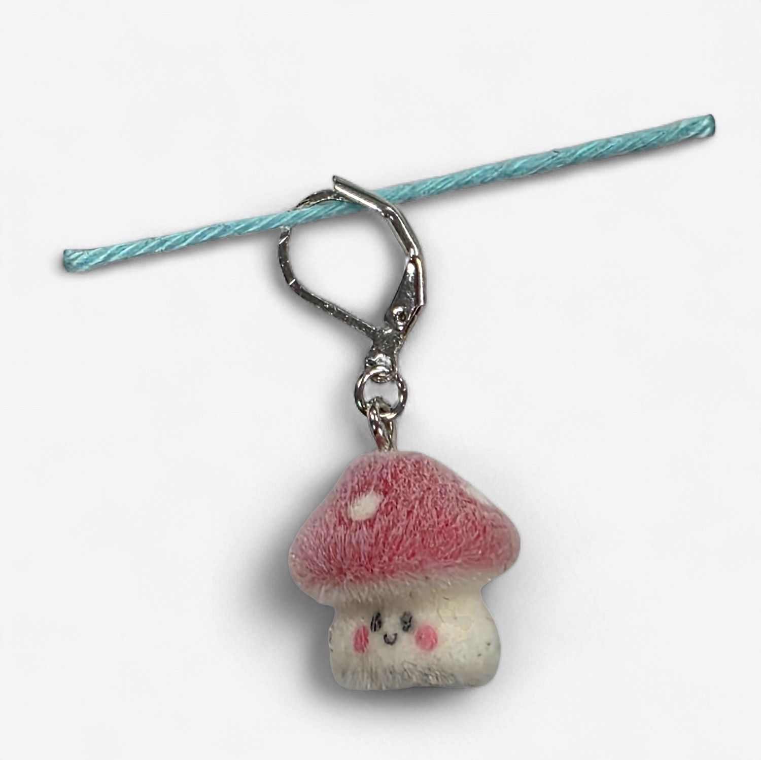 A fuzzy red and cream toadstool shaped stitch marker.