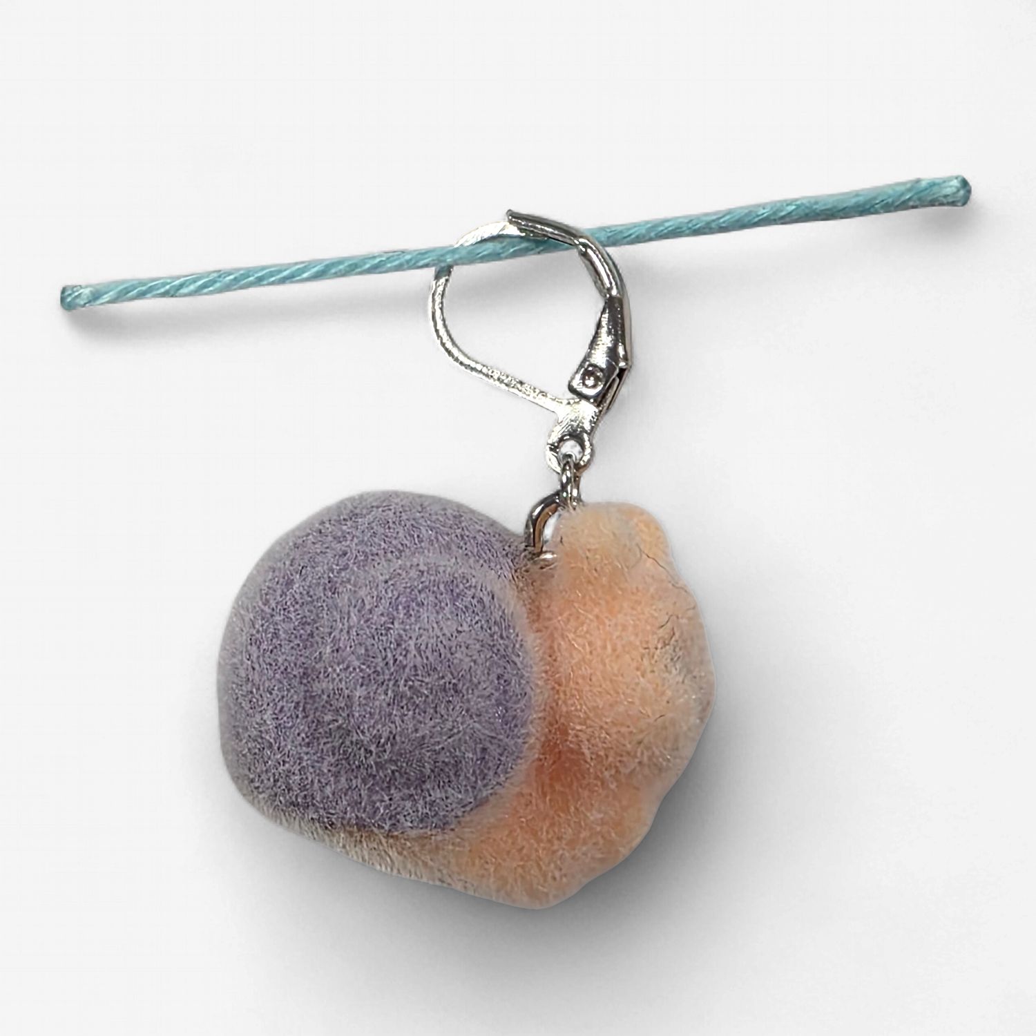 A fuzzy peach and purple snail shaped stitch marker.