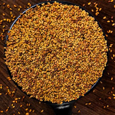 Alfa Alfa seeds piled in a black bowl, showcasing their tiny golden-brown grains and distinctive natural texture.