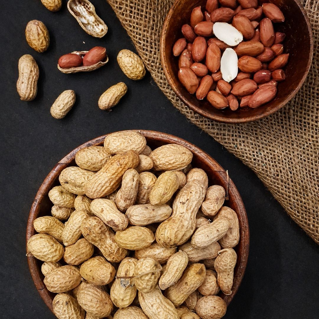 Organic raw peanuts in shells with shelled kernels, highlighting their natural texture, earthy colour and wholesome appeal.