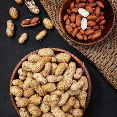 Organic raw peanuts in shells with shelled kernels, highlighting their natural texture, earthy colour and wholesome appeal.