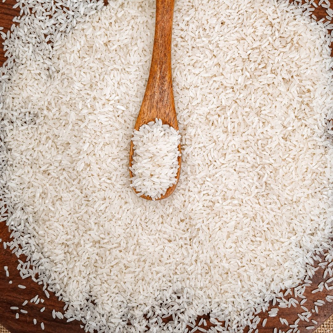 Organic Sona Masuri rice grains with a wooden spoon, showcasing fine texture and natural whiteness for everyday Indian meals.