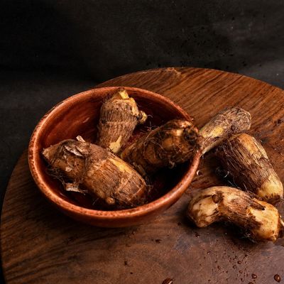 Organic arbi (taro root), fresh colocasia tubers with rough brown skin for traditional Indian cooking.