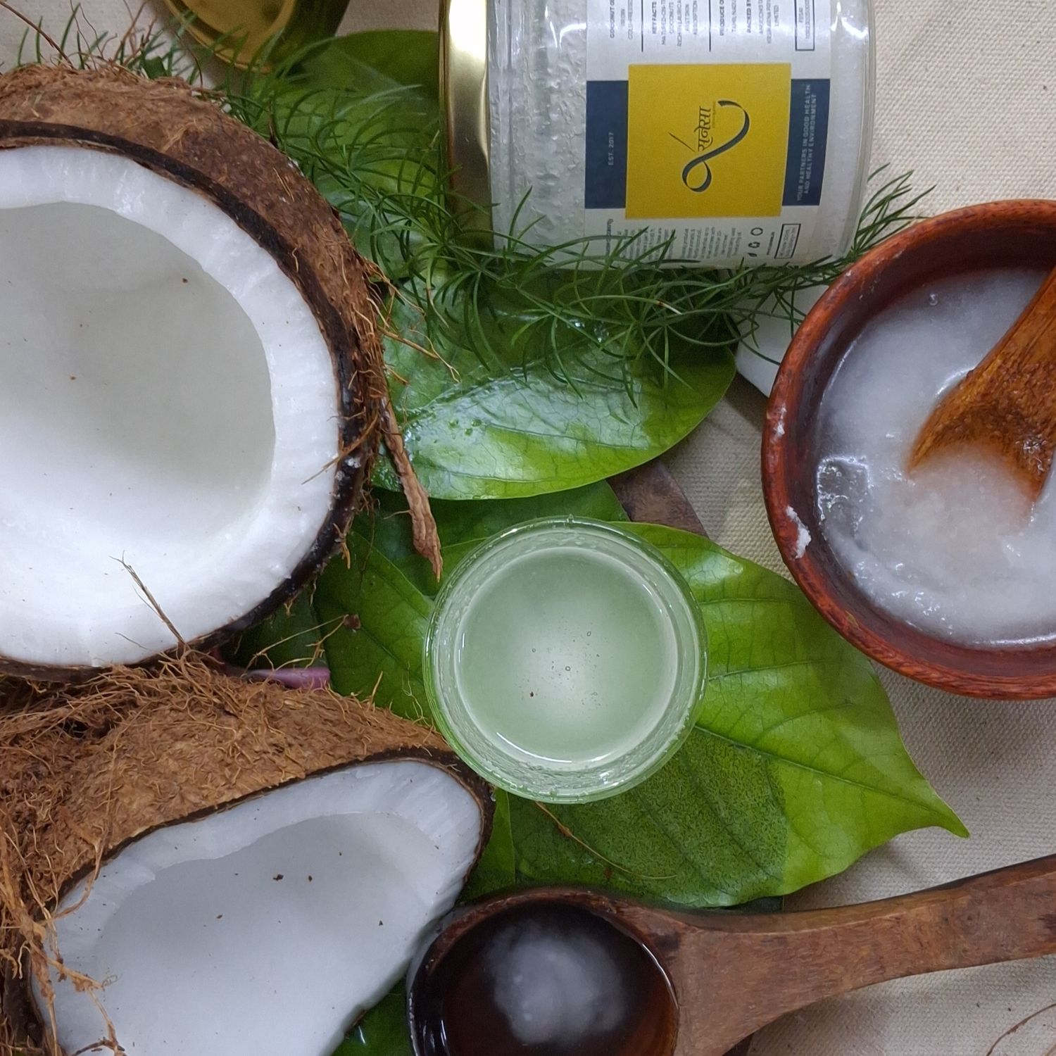 Organic virgin cold-pressed coconut oil with fresh coconut halves, leaves and natural ingredients, ideal for healthy cooking.
