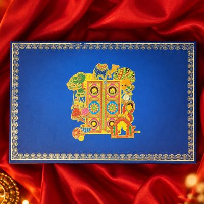 Large festive gift box in royal blue with gold borders and colorful Indian motifs, presented on red satin for Diwali gifting.
