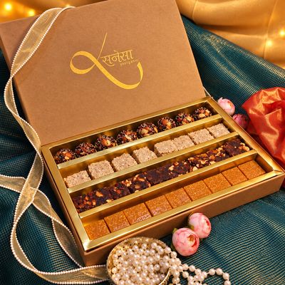 Sanesa's signature brown festive mithai gift box opens to show assorted Indian sweets neatly arranged in ornate golden trays.