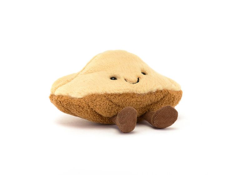 Jellycat Margaux Madeleine plush shaped like a classic French madeleine cake with soft textured detail and smiling face