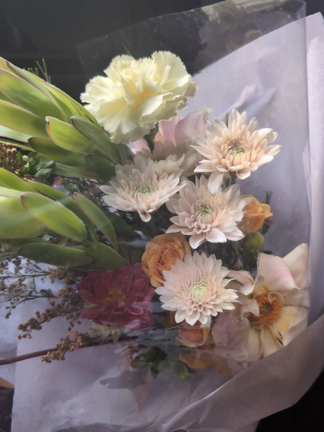 Soft Haze hand-tied bouquet featuring peach and butter-yellow blooms wrapped in white paper — Coco Fleur Curated Edit.