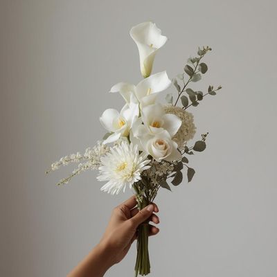Sculptural white floral arrangement held by hand, featuring calla lilies, roses, and seasonal stems in CocoFleur’s signature 