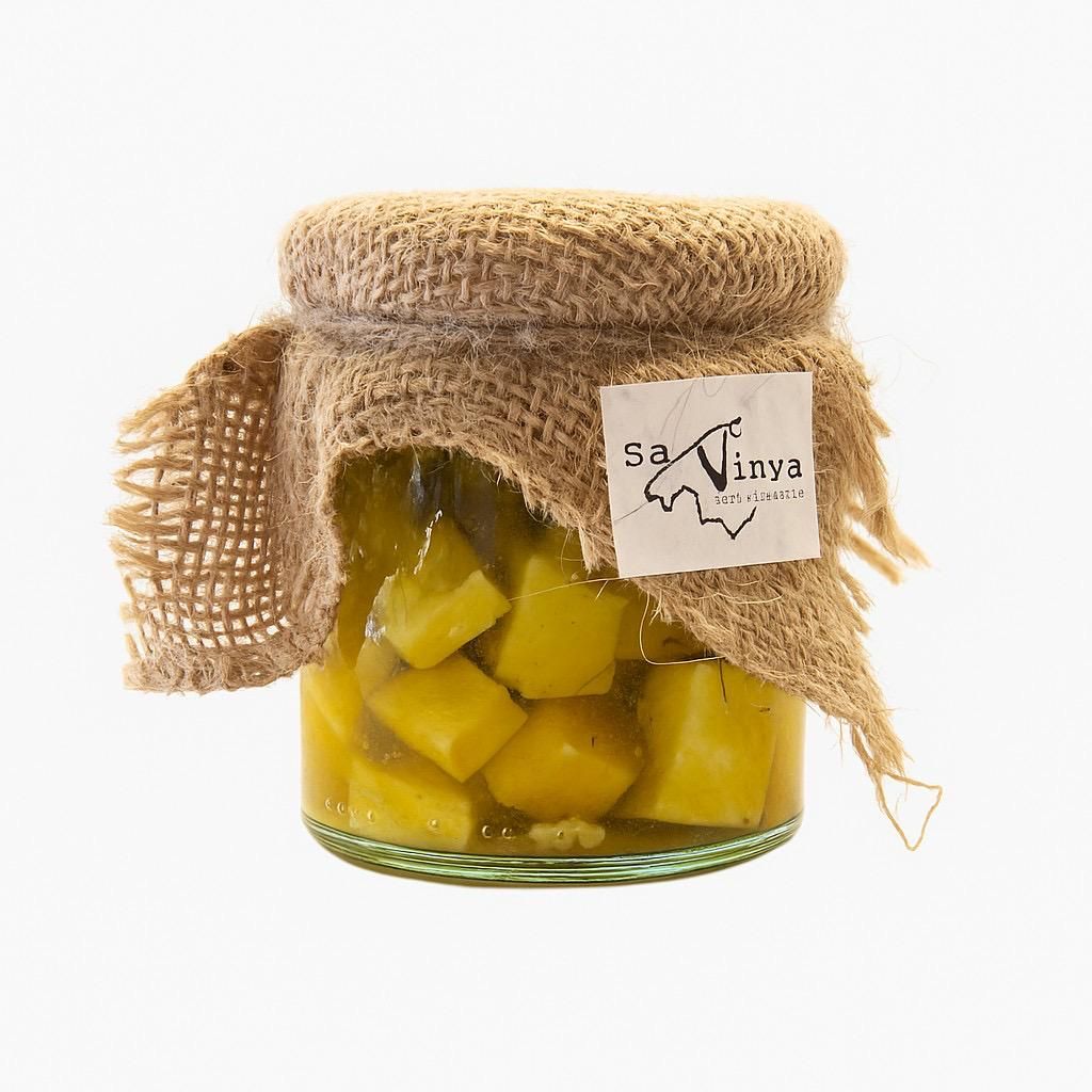 Glass jar with cubes of cured cow&#39;s raw milk cheese in olive oil, garlic, bay leaf, chili pepper, and rosemary approx. 400 GR