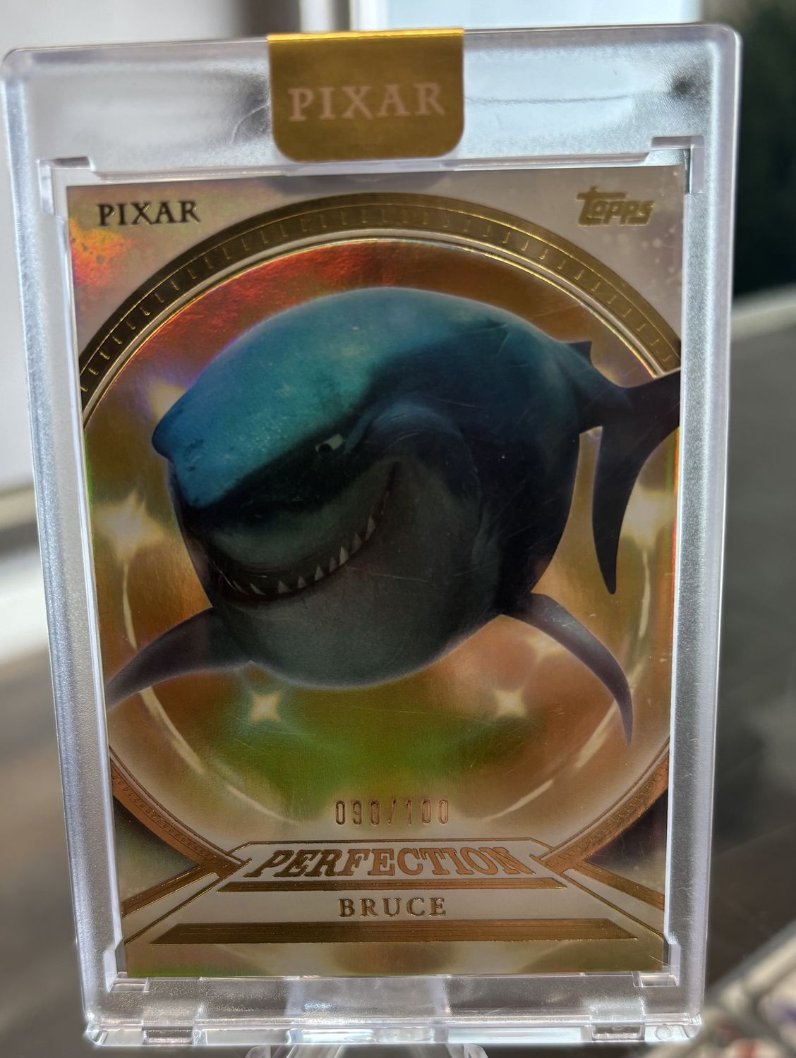 2025 Topps Pixar Gold #PP-24 Bruce Perfection Encased Holo (90/100)