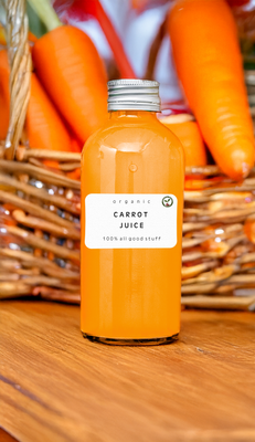 Bottle of Carrot Juice with fresh carrots and greens