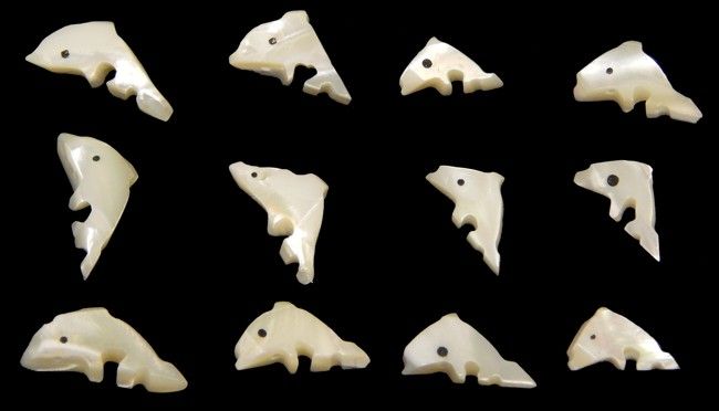 One carved dolphins from troca shell measuring 1/2 to 3/4 inch. *****